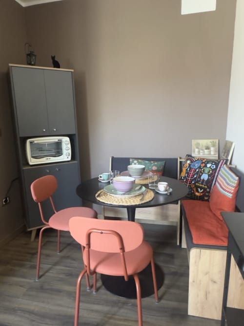 Accogliente zona pranzo al Casale Rusignûl B&B con sedie coralline, tavolo rotondo nero e angolo cottura a Cassegliano