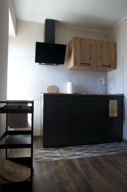 Cucina moderna a Casale Rusignûl B&B a Cassegliano con mobili neri, pensili in legno e acciaio inox