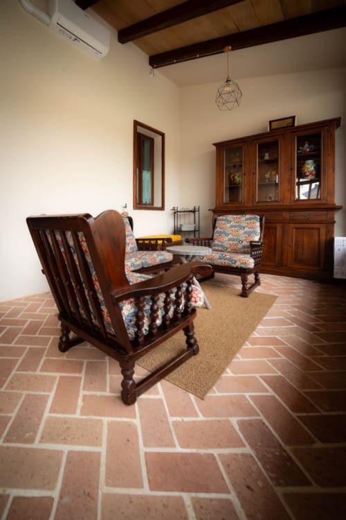 Soggiorno rustico al Casale Rusignûl B&B in Toscana con mobili in legno, cuscini decorati e pavimenti in cotto
