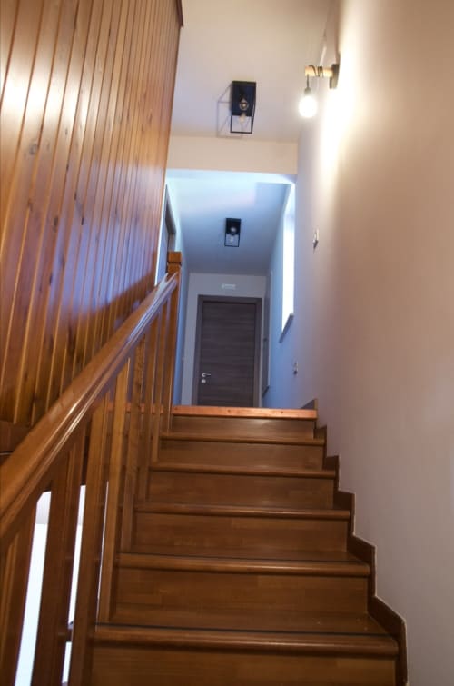 Scalone in legno con ringhiera che conduce al corridoio blu della Casale Rusignûl B&B a Cassegliano, Italia