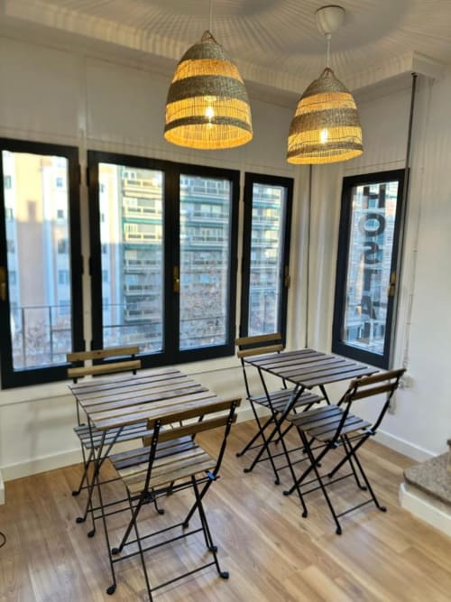 Acogedor salón del Hostal Zaragoza Centro con asientos de barra a rayas, lámparas colgantes tejidas y vistas de la ciudad