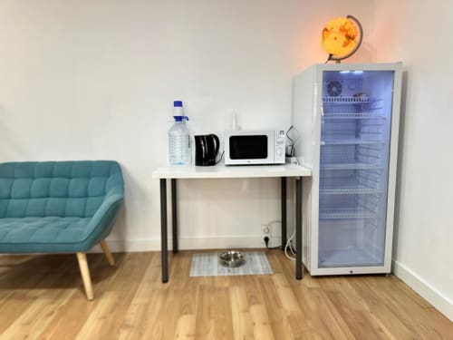 Sala de descanso moderna del Hostal Zaragoza Centro con sofá turquesa, cocineta, microondas, minibar y lámpara globo