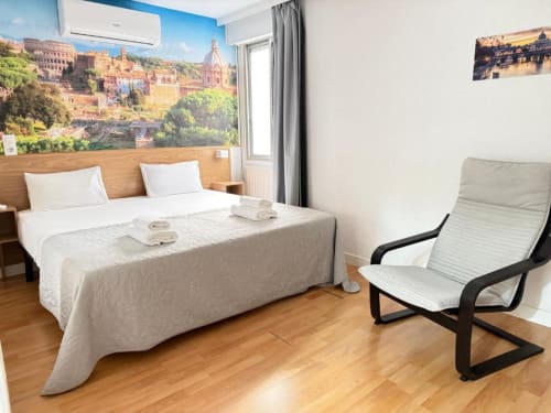 Habitación deluxe en Hostal Zaragoza Centro con cama king-size, mobiliario moderno, suelo de madera y mural con vista de la ciudad