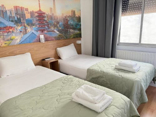 Camas gemelas en Hostal Zaragoza Centro con vistas de la ciudad, almohadas blancas, edredones verdes y ventana con vista a Zaragoza
