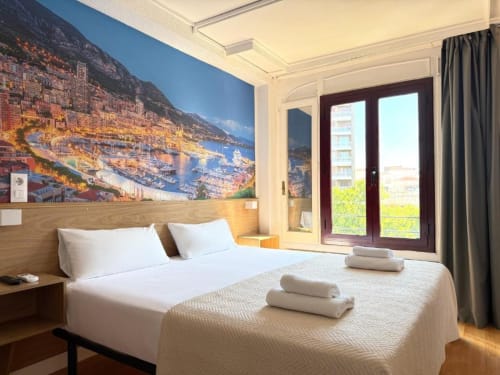 Habitación Deluxe en Hostal Zaragoza Centro con cama king-size, mural con vistas a la ciudad y mobiliario moderno
