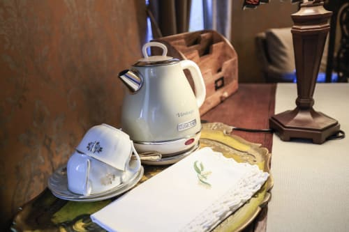 Bouilloire électrique blanche avec tasse de thé et serviettes sur la table à La Maison Oubliée B&B, Goetzenbruck
