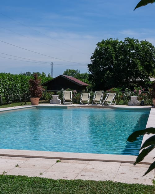 Area piscina di Corte Pellegrini a Verona con lettini, giardini rigogliosi e acqua cristallina