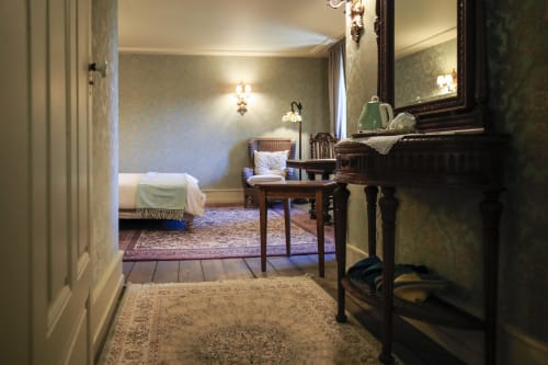 Élégante chambre vintage à La Maison Oubliée à Goetzenbruck, France, avec papier peint damassé vert et mobilier d'époque