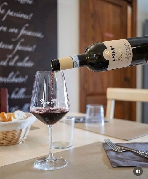 Vino Ilatum versato in un bicchiere presso Corte Pellegrini B&B a Verona, con tavolo apparecchiato sullo sfondo