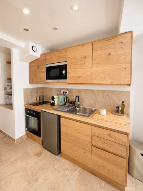 Cuisine moderne de l'appartement By Elodie à Hyères, avec meubles en bois, électroménagers inoxydable et sol carrelé