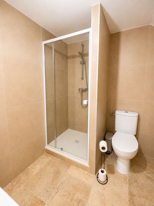 Salle de bain moderne avec douche fermée, toilettes blanches et carrelage beige à l'appartement By Elodie à Hyères