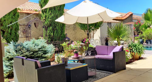 Magnifique terrasse piscine aux Villas Lux Tropical à Béziers avec mobilier violet, parasols, plantes tropicales et pierre