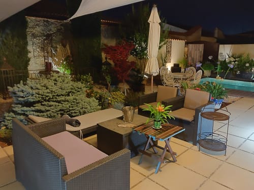 Élégante terrasse nocturne aux Villas Lux Tropical, Béziers avec sièges détente, plantes fleuries et parasol près de la piscine