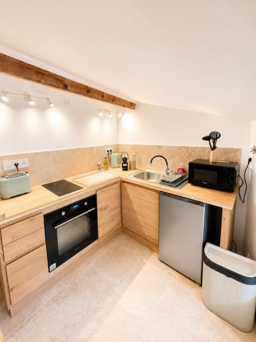 Cuisine moderne avec meubles en bois, électroménagers en acier inoxydable et plan de travail en pierre claire, appartement By Elodie, Hyères