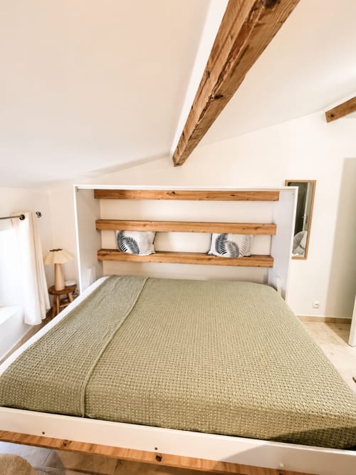 Chambre moderne avec tête de lit en poutre bois, literie beige et vue sur la ville dans l'appartement By Elodie, Hyères