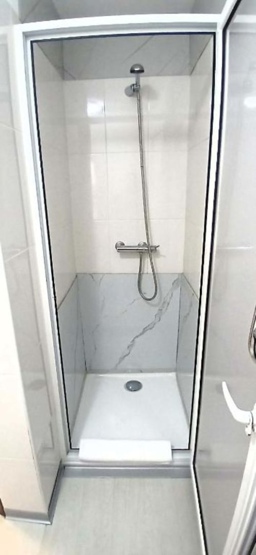 Chuveiro moderno com revestimento em tom de mármore e acabamento cromado no quarto do hotel Madeirarooms, Funchal