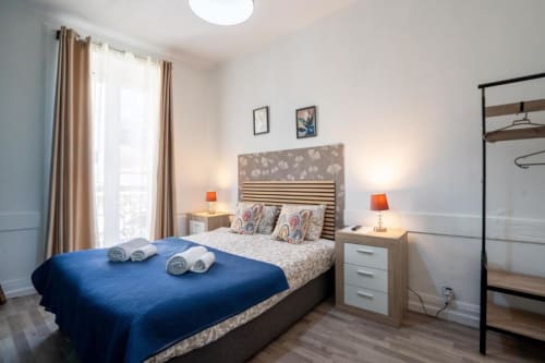 Quarto duplo moderno na Madeirarooms em Funchal com manta azul, varanda com vista para a cidade e móveis contemporâneos
