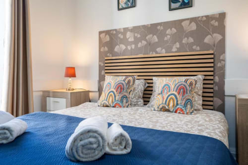 Quarto duplo moderno no hotel Madeirarooms em Funchal com cabeceira listrada, almofadas estampadas e toalhas enroladas