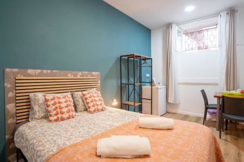 Quarto duplo moderno em Madeirarooms Funchal com parede de destaque turquesa, cabeceira listrada e roupa de cama laranja estampada