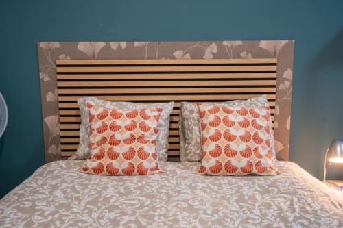 Cama de casal no Madeirarooms Funchal com cabeceira listrada, roupa de cama estampada e almofadas com padrão de conchas coral sobre fundo azul-petróleo
