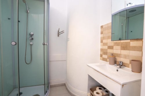Banheiro moderno em Madeirarooms Funchal com chuveiro de vidro, azulejos bege, bancada branca e local para papel higiênico