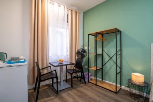 Quarto duplo moderno no Madeirarooms Funchal com parede de destaque verde, secretária, guarda-roupa em vidro e vista para a cidade