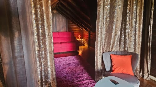 Chambre de villa luxueuse avec rideaux or scintillants, sièges garnis rose, coussin orange et ambiance lumineuse chaleureuse