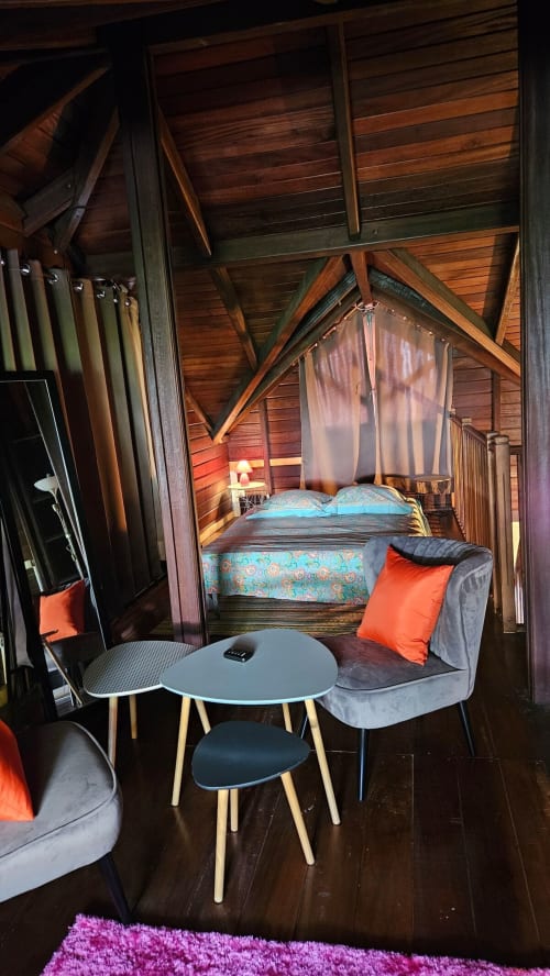 Chambre élégante de villa moderne aux poutres en bois, literie turquoise, sièges gris, accents orange et vue piscine à Villa La Suite Viva