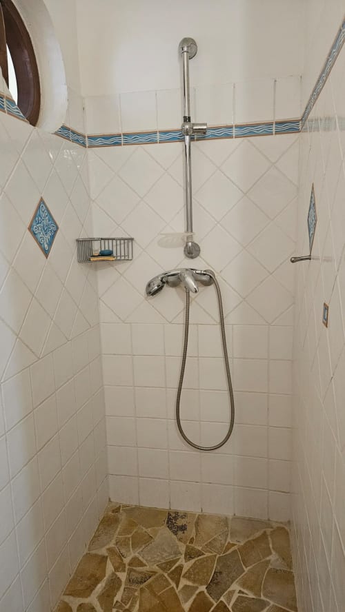 Salle de bains moderne de la Villa Calebassier avec douche pluie et douchette, carrelage blanc losange et éléments décoratifs