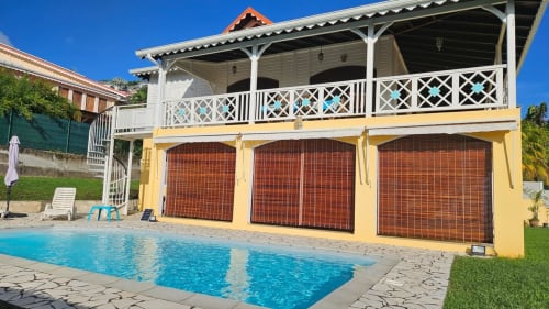 Villa La Suite Viva Vero avec piscine bleue, maison d'hôtes jaune, portes rouges et balustrade blanche sous ciel dégagé
