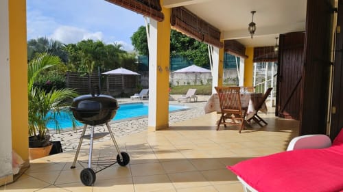Terrasse couverte avec barbecue vue sur la piscine à la Villa Calebassier, resort tropical caribéen