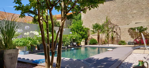 Villa tropicale à Béziers avec piscine turquoise, espaces détente, arbres matures et murs en pierre