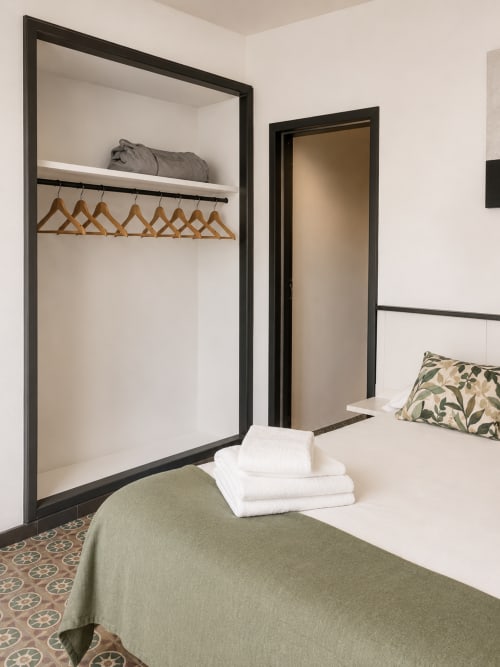 Modern bedroom at Mas Ribas Hotel in Palamos with open wardrobe, wooden hangers, and garden view
