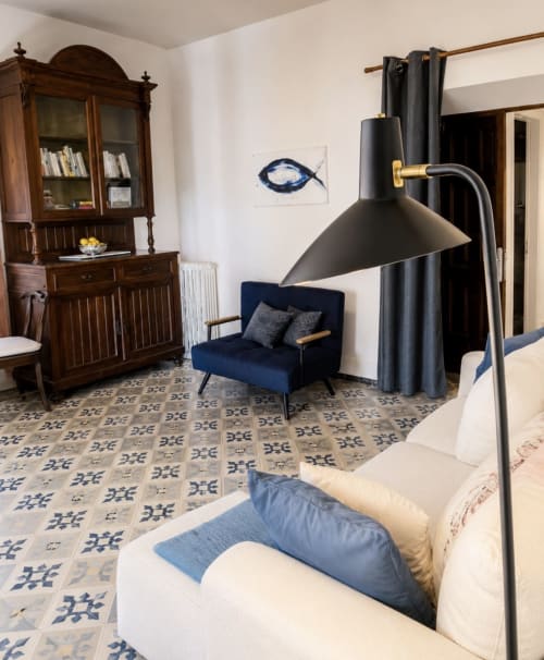 Elegant habitació a l'hotel Mas Ribas de Palamós amb butaca blava, llum de peu negre, rajoles amb patrons i mobles de fusta