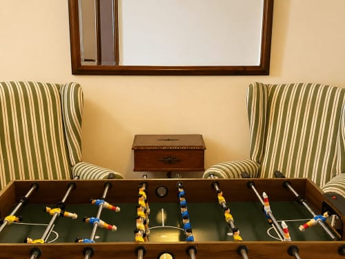 Mesa de futbolín en el salón de la cabaña Vila Santa Rita de Holibai, Oia, con sillones tapizados y espejo