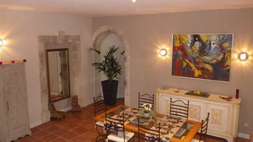 Salle à manger élégante avec table en bois, voûte, œuvres d'art colorées et éclairage ambiant à la villa Villas Lux Tropical.