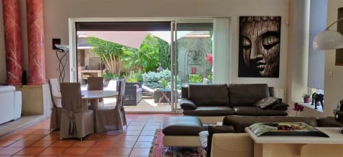 Salon de villa de luxe à Béziers avec canapé en cuir noir, carrelage en terre cuite et vue sur la piscine du jardin