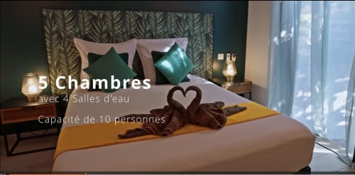 Chambre luxueuse aux accents verts, serviettes en forme de cœur et vue sur mer aux Villas Lux Tropical, Saint-Pierre Réunion