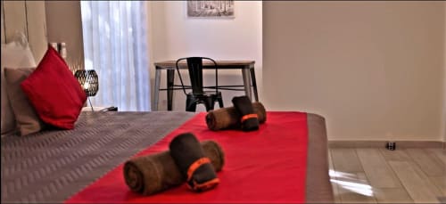 Chambre de villa moderne aux accents rouges, gants de boxe sur le lit, coin repas et lumière naturelle abondante aux Villas Lux Tropical