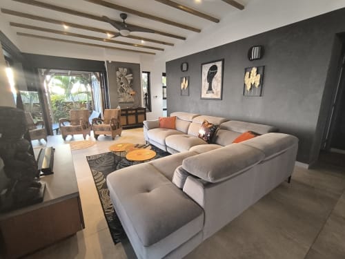 Salon moderne de villa avec canapé sectionnel beige, mur d'accent gris et vue tropicale à Villas Lux Tropical, Saint-Pierre