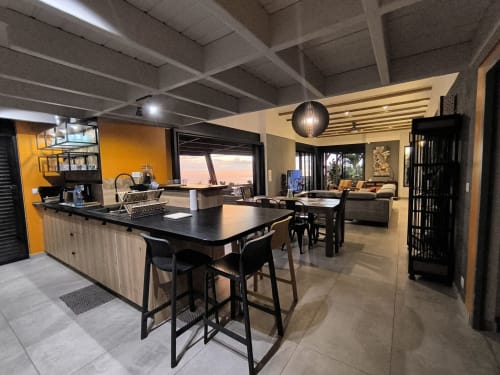 Cuisine et salle à manger de villa moderne avec vue sur mer, Saint-Pierre Réunion. Table noire, mur jaune, espace ouvert