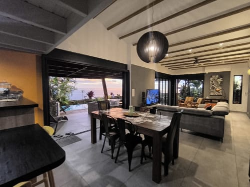 Villa de luxe à Saint-Pierre, séjour avec salle à manger, vue océan par portes coulissantes, terrasse piscine et décor moderne