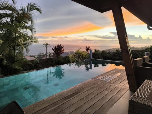Vue du coucher de soleil depuis la terrasse de la piscine chauffée de la Villa Lux Cap Austral avec océan et palmiers tropicaux, Saint-Pierre Réunion