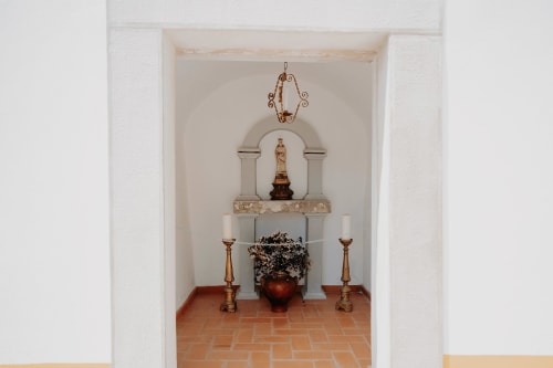 Rustic chapel altar at Casa de Campo da Quinta da Pegada, Óbidos with religious statue, candles and decorative elements