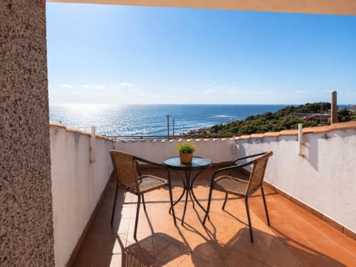 Terraza de la casa Vila Santa Rita en Oia con vistas al mar, mesa y sillas frente a la costa mediterránea