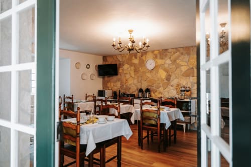 Sala de refeições da Casa de Campo da Quinta da Pegada em Óbidos com mesas de madeira, toalhas brancas e decoração tradicional.