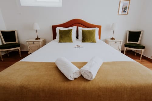 Quarto duplo deluxe da Casa de Campo da Quinta da Pegada em Óbidos com toalhas enroladas, almofadas verde-oliva e vista para o jardim