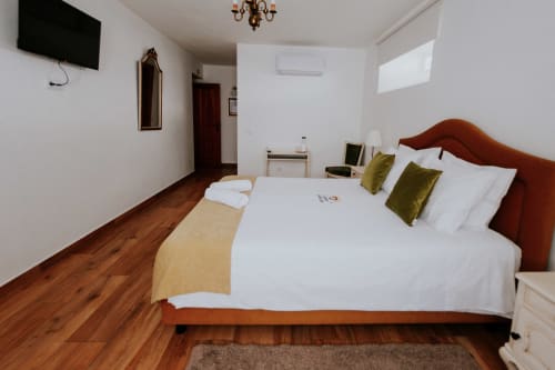 Quarto Duplo Deluxe com cama rústica, almofadas verdes, assoalho de madeira e vista para jardim em Óbidos