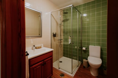 Casa de banho moderna com azulejos verdes no duche, lavatório vermelho e sanita no quarto de luxo da Casa de Campo da Quinta da Pegada, Óbidos