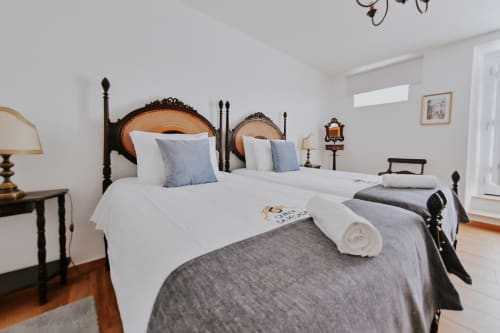 Quarto de casal elegante na Casa de Campo da Quinta da Pegada em Óbidos com cama de dossel, roupa de cama branca e vista para o jardim